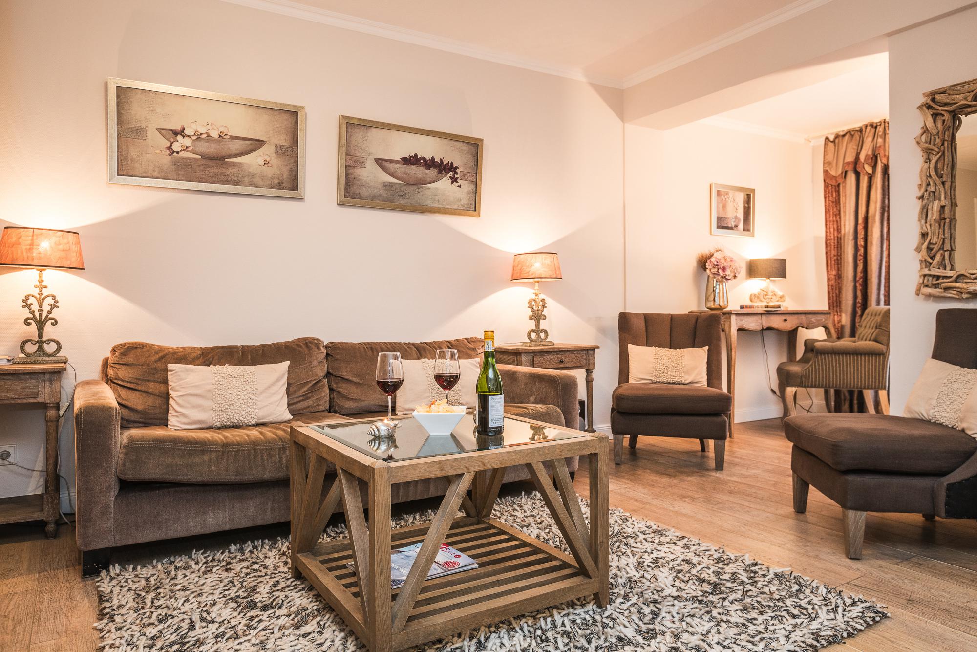 Foto zeigt ein Zimmer vom Hotel Sylter Hahn mit Couch, zwei Sessel und einem Schreibtisch.