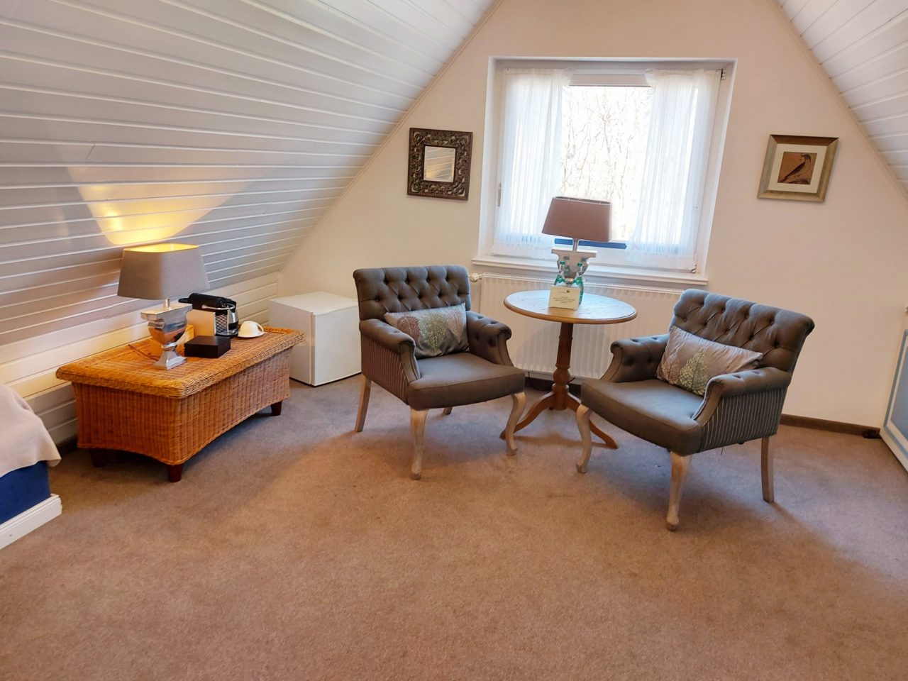 Wohnzimmer mit zwei Sesseln und Couchtisch mit Willkommensgetränken im Doppelzimmer Hotel Sylter Hahn.