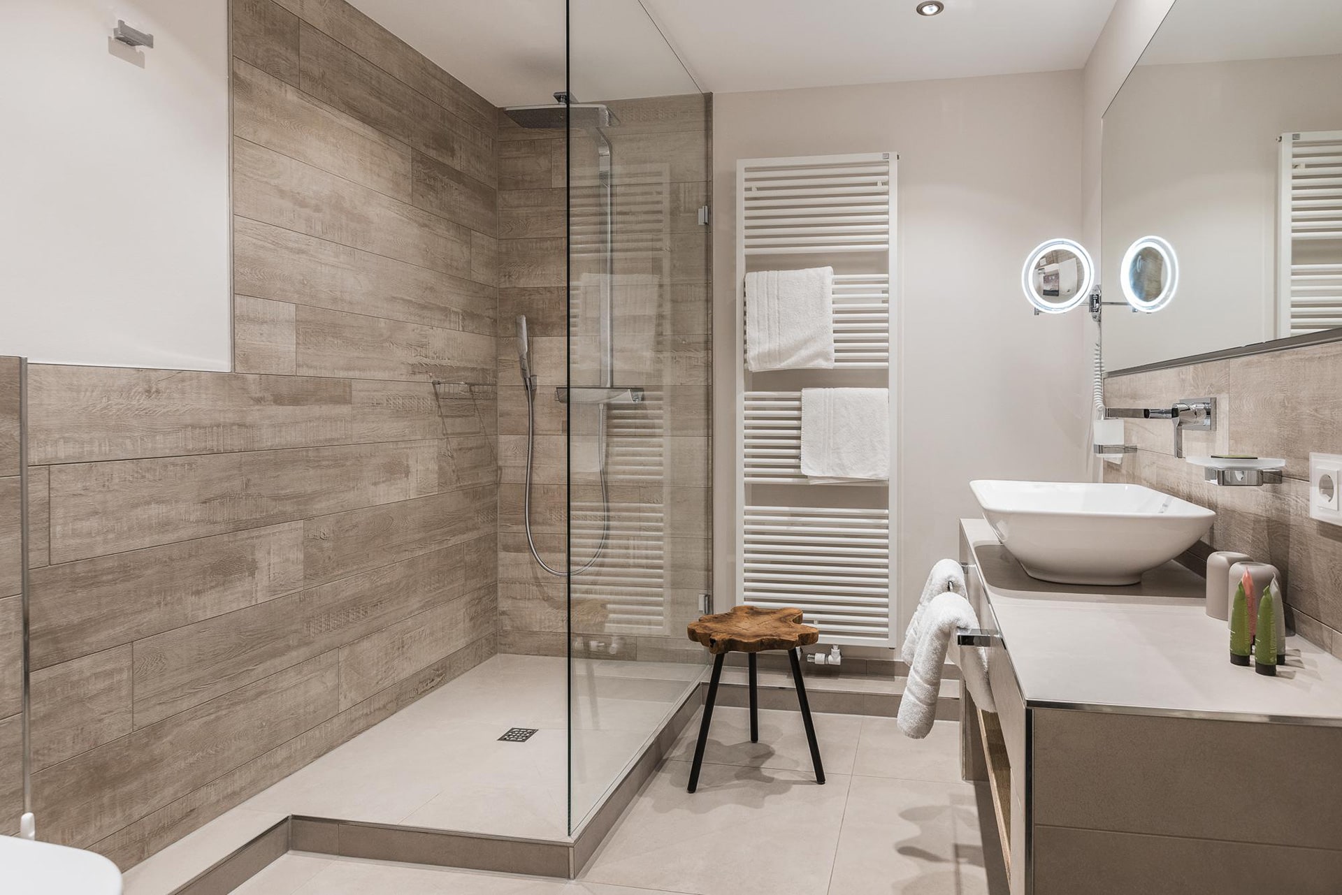 Modernes Badezimmer mit Dusche und Holzhocker im Doppelzimmer im Hotel Landhaus Sylter Hahn in Westerland auf Sylt.