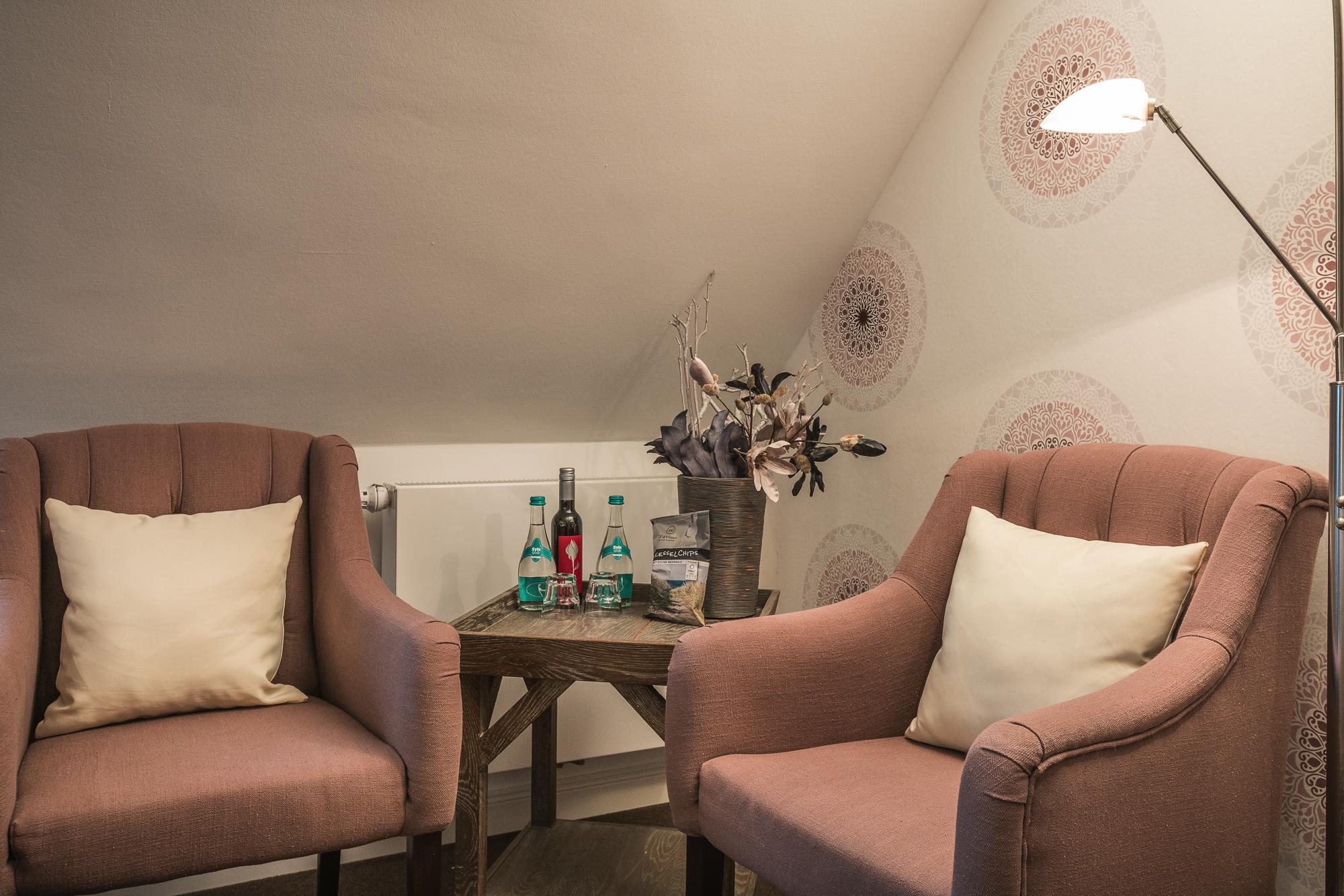 Doppelzimmer mit Bett, zwei Sesseln, Musikbox, Willkommensgetränk, Holzkommode und Fernseher im Landhaus Sylter Hahn.
