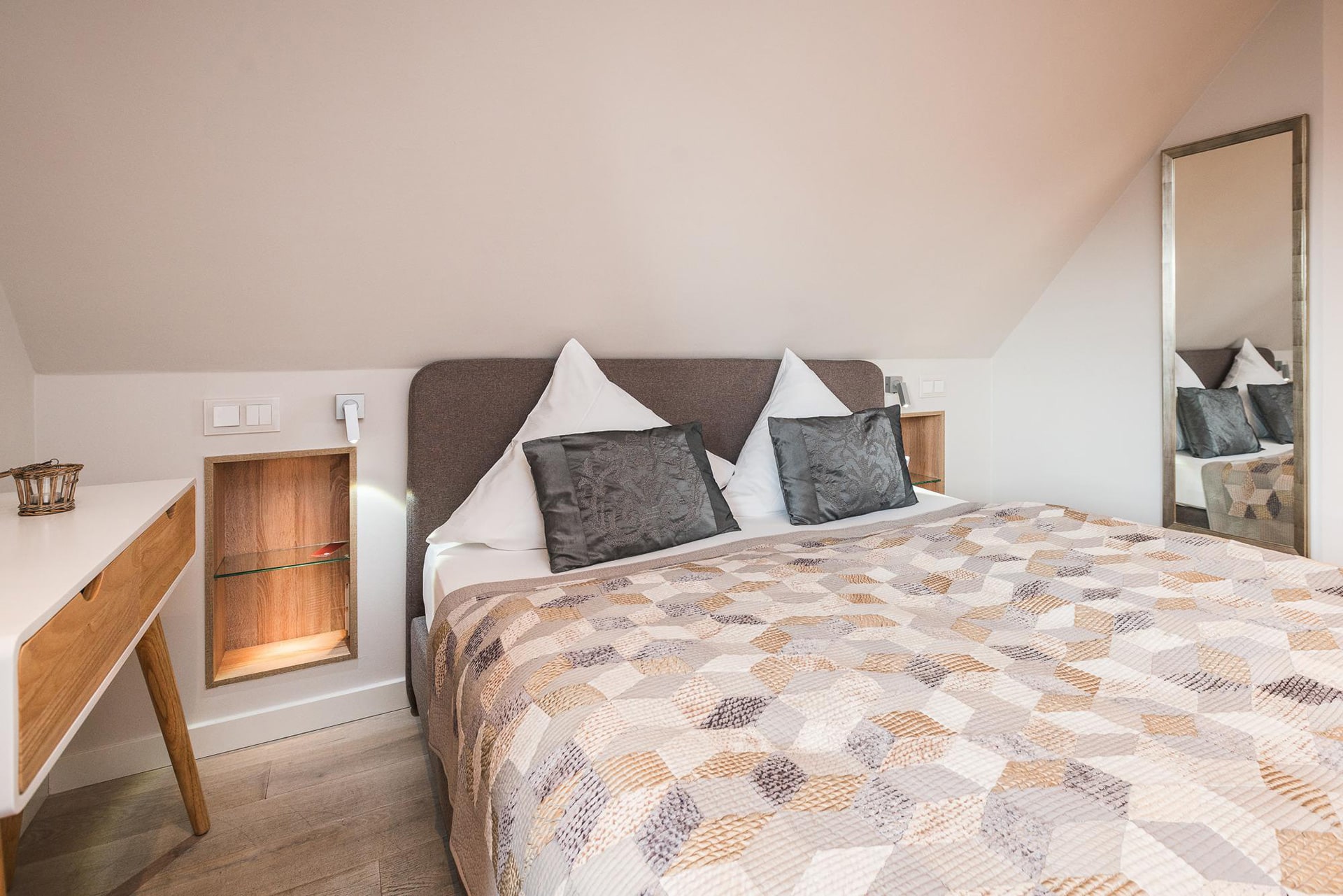 Doppelzimmer mit Doppelbett mit Überwurf und vielen Kissen im Hotel Landhaus Sylter Hahn in Westerland auf Sylt.
