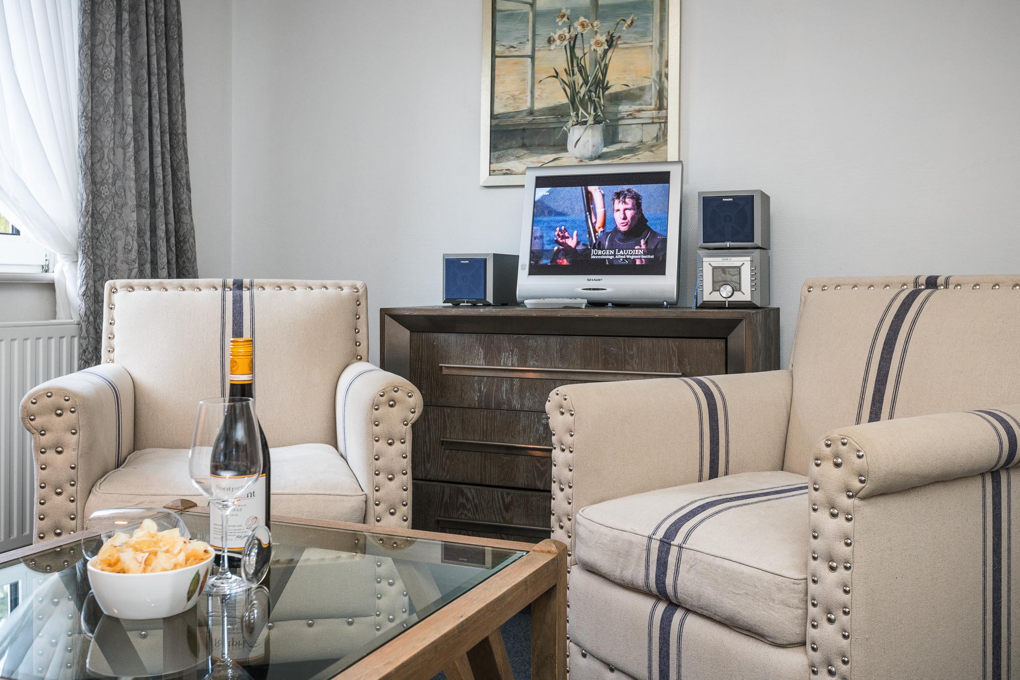 Gemütliches Doppelzimmer mit Doppelbett, zwei Sesseln und Willkommensgetränken auf einem Beistelltisch im Hotel Landhaus Sylter Hahn.