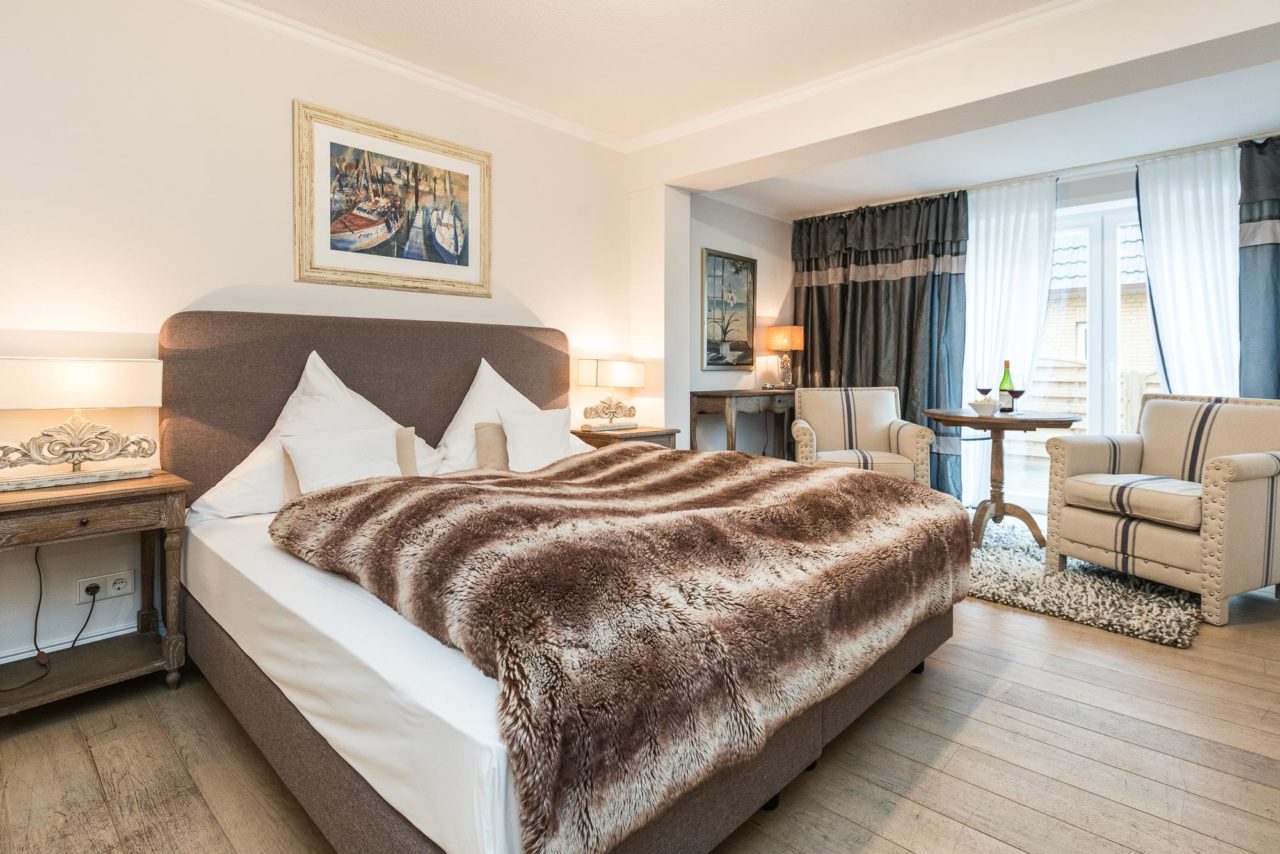 Modernes Doppelzimmer mit Doppelbett, zwei Holznachttischen im Hotel Landhaus Sylter Hahn in Westerland.