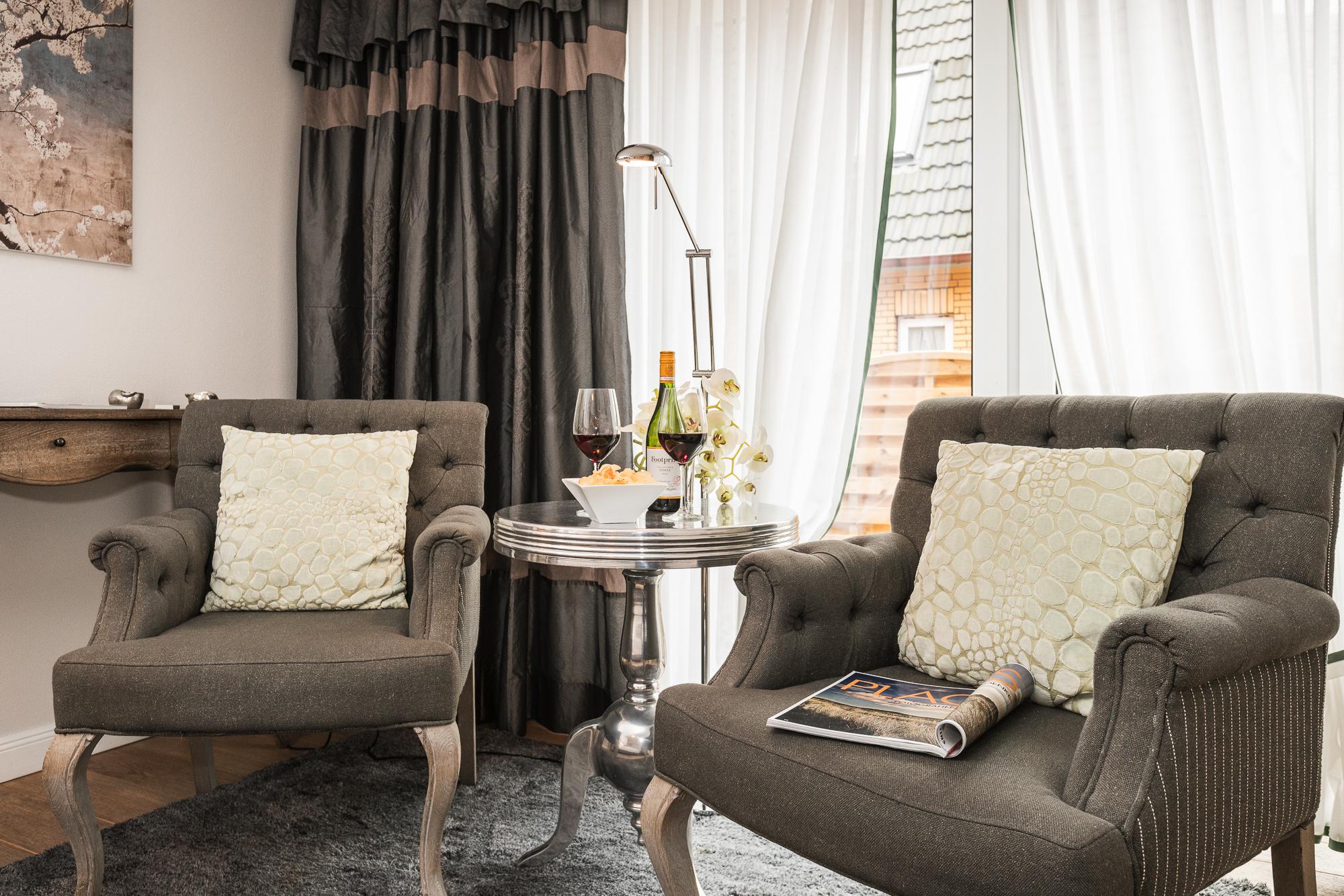Doppelzimmer mit zwei englischen Sesseln, Beistelltisch und Blumen im Hotel Landhaus Sylter Hahn in Westerland auf Sylt.