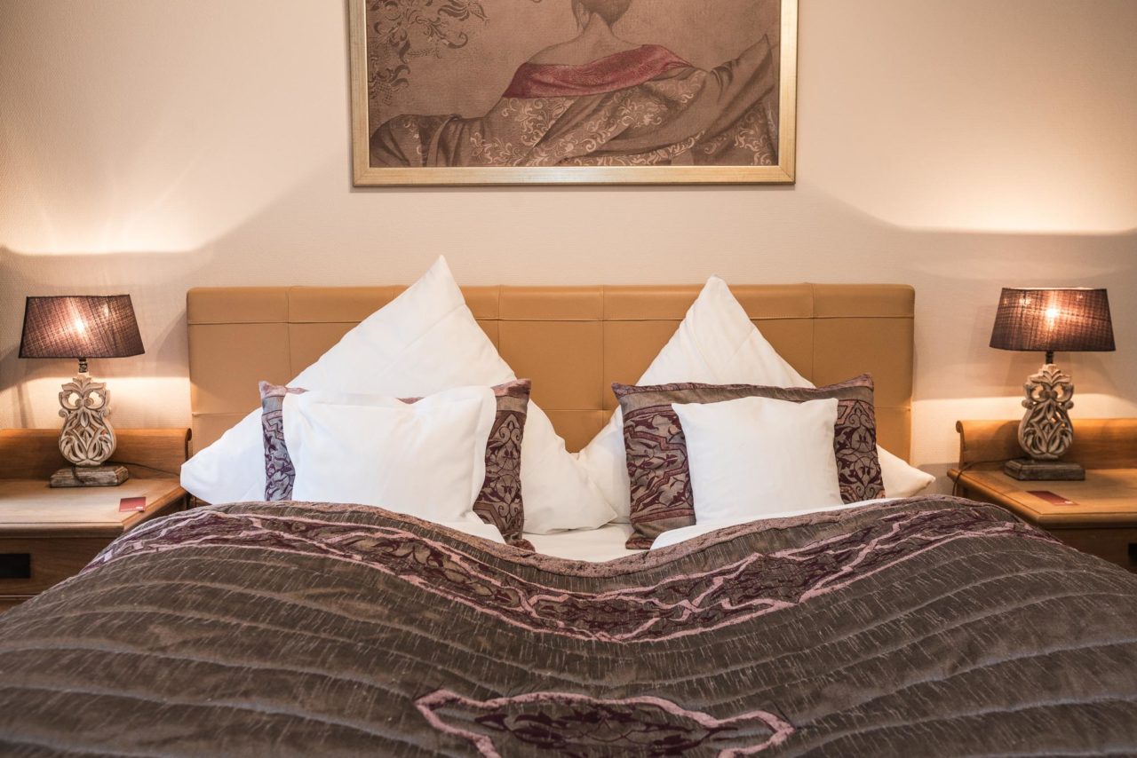 Modernes Doppelzimmer mit Doppelbett und zwei Holznachttischen im Hotel Landhaus Sylter Hahn in Westerland.