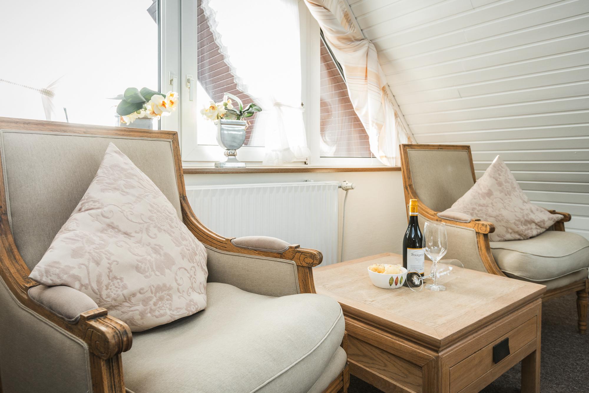 Wohnzimmer mit Sesseln und Fernseher im Doppelzimmer unter dem Dach vom Hotel Landhaus Sylter Hahn in Westerland auf Sylt.