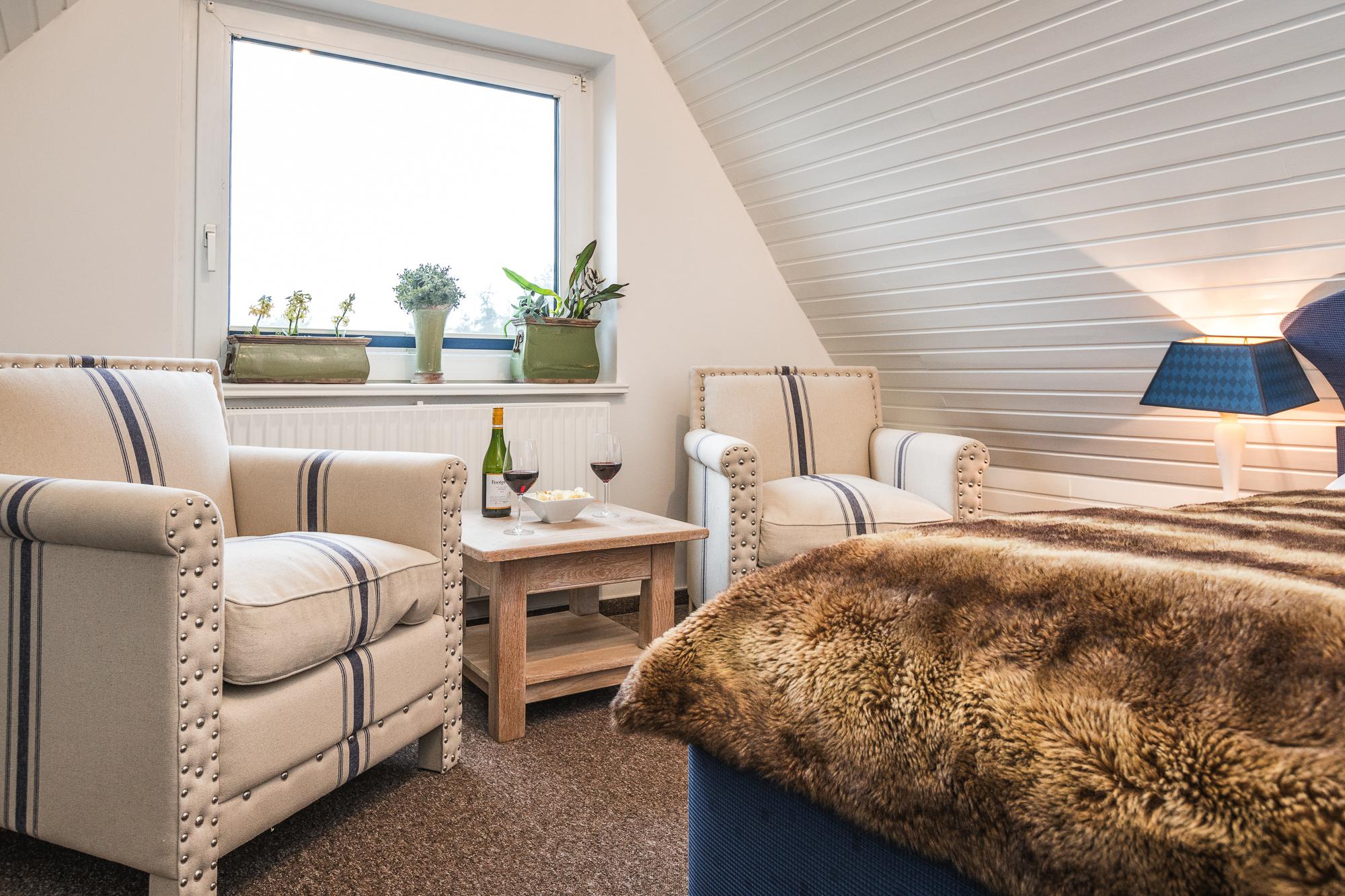 Wohnzimmer mit zwei Sesseln, Couchtisch und Willkommensgetränken im Doppelzimmer Hotel Sylter Hahn.