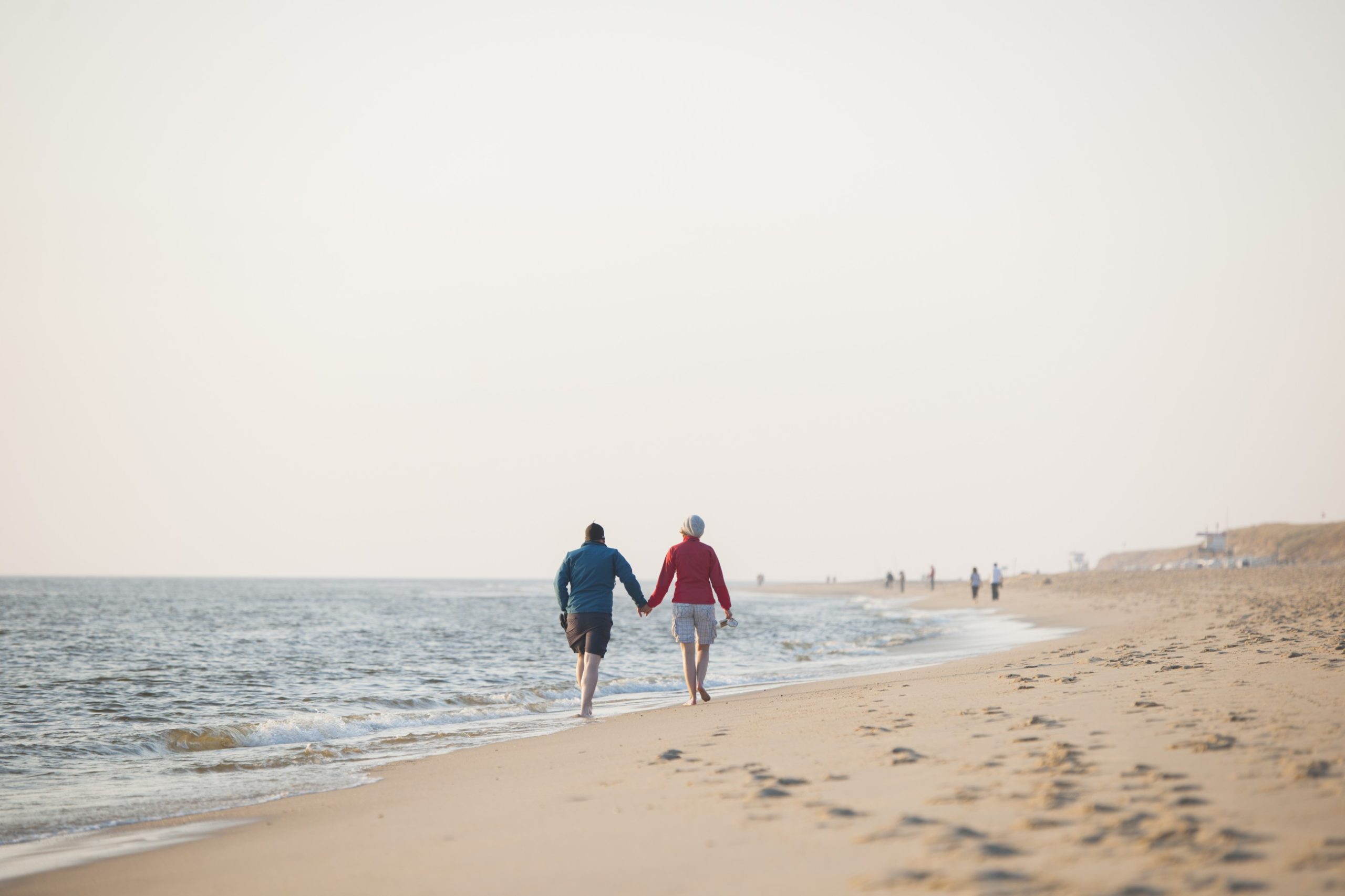 Ein Mann und eine Frau gehen Hand in Hand am Strand von Westerland auf Sylt spazieren.